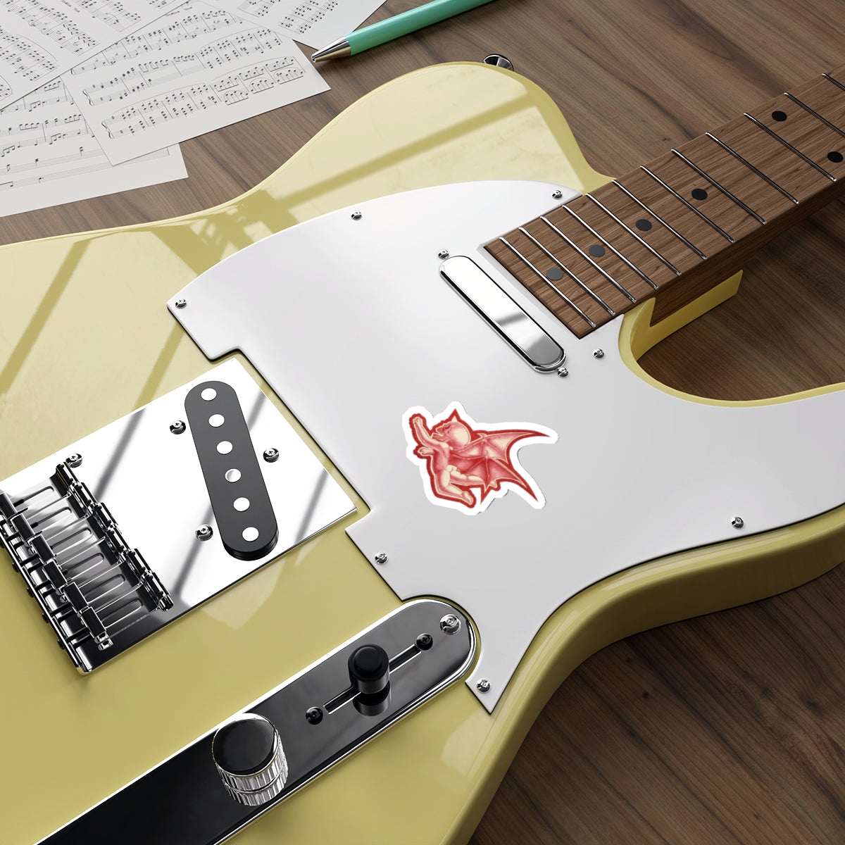 A mock up of my original design Aourim © as a sticker in Red monochrome with a white boarder of a winged creature with a skull on a white background on a mock up green electric guitar